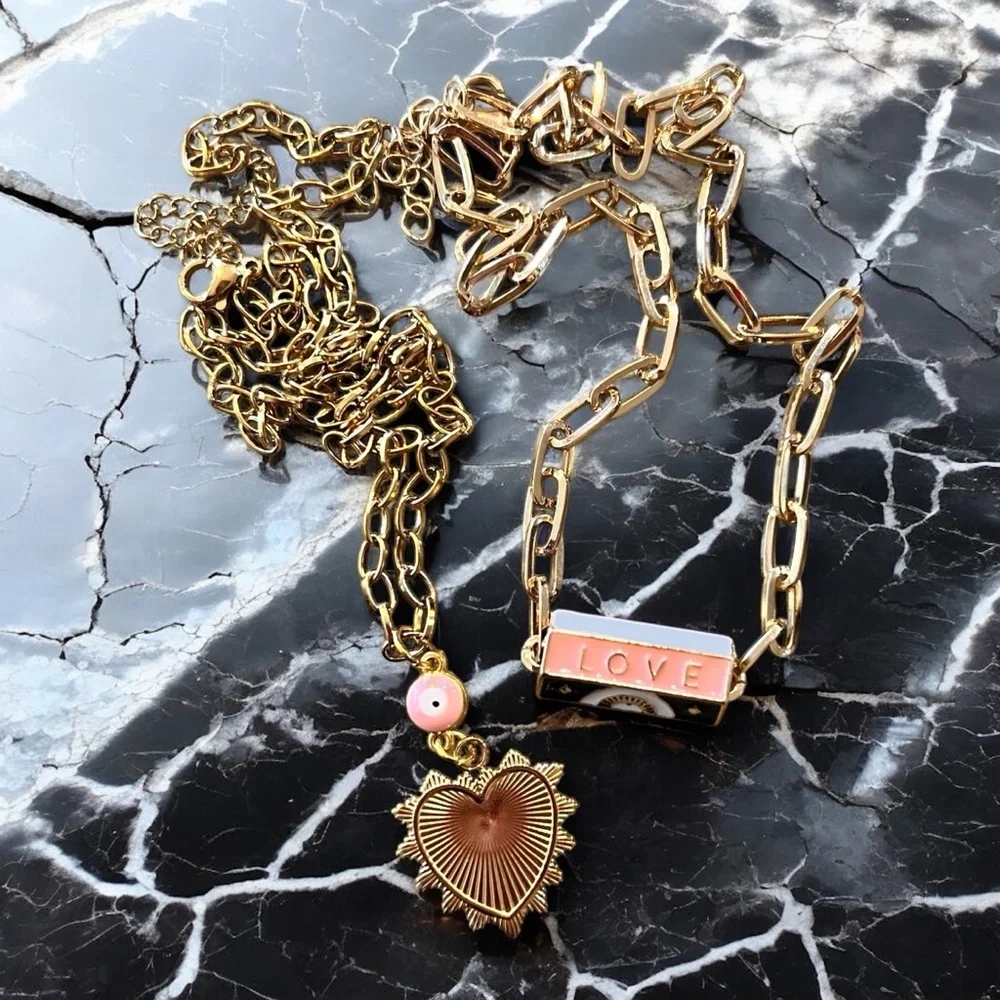 Gold toned chains with black, white, gold, and pastel pink enamel charms.